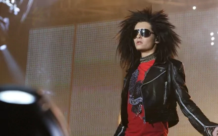 HD PC desktop wallpaper featuring Tokio Hotel's lead singer with spiky hair and sunglasses, performing on stage under bright lights.