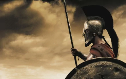 HD wallpaper featuring Gerard Butler as King Leonidas from the movie 300, holding a spear and shield against a dramatic, cloudy sky background.