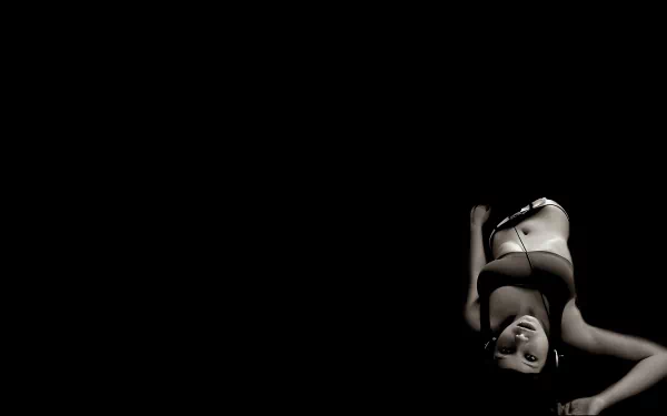 A black and white HD desktop wallpaper features a woman wearing headphones, immersed in music, capturing a moment of relaxation and enjoyment in a minimalistic setting.