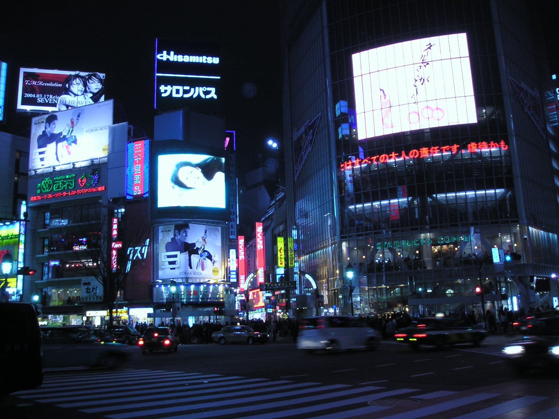 HD PC desktop wallpaper background: Tokyo night street intersection lit by neon billboards and large movie posters, cinematic urban skyline with traffic and glowing signs.