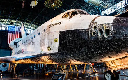 Space Shuttle Discovery vehicle as an HD PC desktop wallpaper and background: close-up of its nose, cockpit windows and black thermal tiles inside a museum hangar.