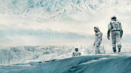 HD desktop wallpaper from the movie Interstellar featuring astronauts walking on a frosty, alien landscape with mountains in the background.