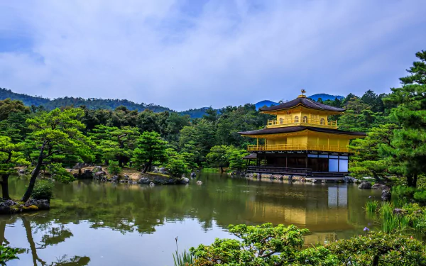 HD desktop wallpaper of Kinkaku-ji (Golden Pavilion) in Kyoto, Japan, reflected in a tranquil pond amid wooded hills and temple gardens, a religious Zen landmark.