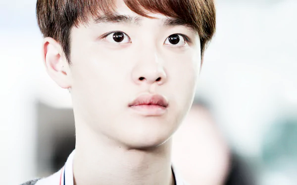 A close-up of a young man with expressive eyes, set against a blurred background. This HD desktop wallpaper captures a moment from EXO's music world.