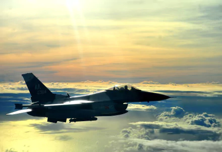 A General Dynamics F-16 Fighting Falcon soars through a vibrant sky, surrounded by clouds, highlighting the power of military aviation. A stunning HD desktop wallpaper.