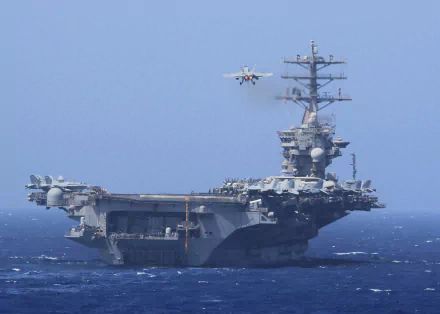A Boeing F/A-18E/F Super Hornet prepares to land aboard the USS Nimitz (CVN-68), a formidable aircraft carrier navigating through the ocean.