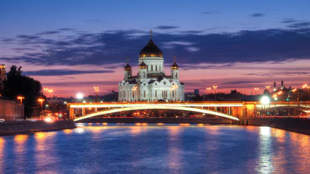 The Cathedral of Christ the Saviour illuminated at dusk, reflected in the river beneath a glowing city bridge, captured in 4K Ultra HD for a stunning desktop wallpaper.
