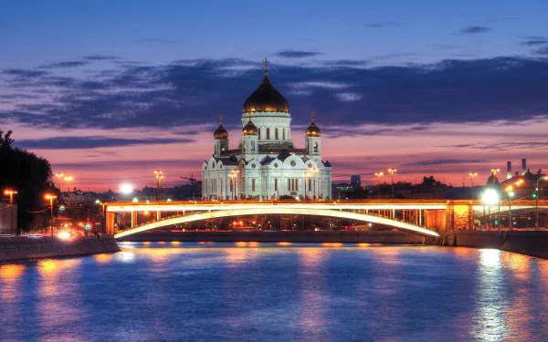 The Cathedral of Christ the Saviour illuminated at dusk, reflected in the river beneath a glowing city bridge, captured in 4K Ultra HD for a stunning desktop wallpaper.