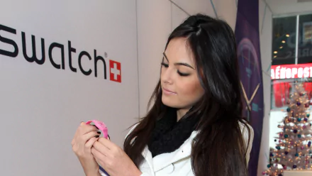 Mexican model in a white coat and black scarf inspects a pink watch — 2K Quad HD PC desktop wallpaper/background.