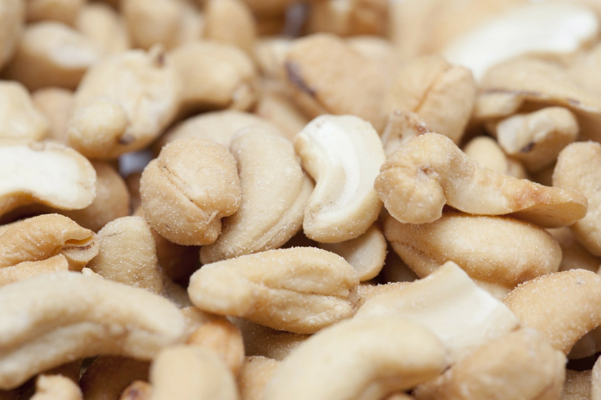 Close-up of shelled cashew nuts piled together; 2K Quad HD PC desktop wallpaper and background featuring food, cashew.