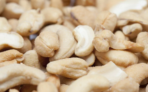 Close-up of shelled cashew nuts piled together; 2K Quad HD PC desktop wallpaper and background featuring food, cashew.