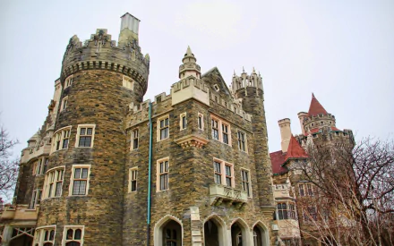 HD PC desktop wallpaper of Casa Loma — a man-made stone castle with towers, turrets, and Gothic detailing against a pale sky.