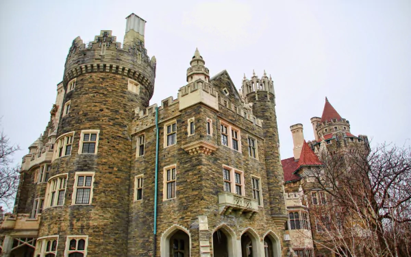 HD PC desktop wallpaper of Casa Loma — a man-made stone castle with towers, turrets, and Gothic detailing against a pale sky.