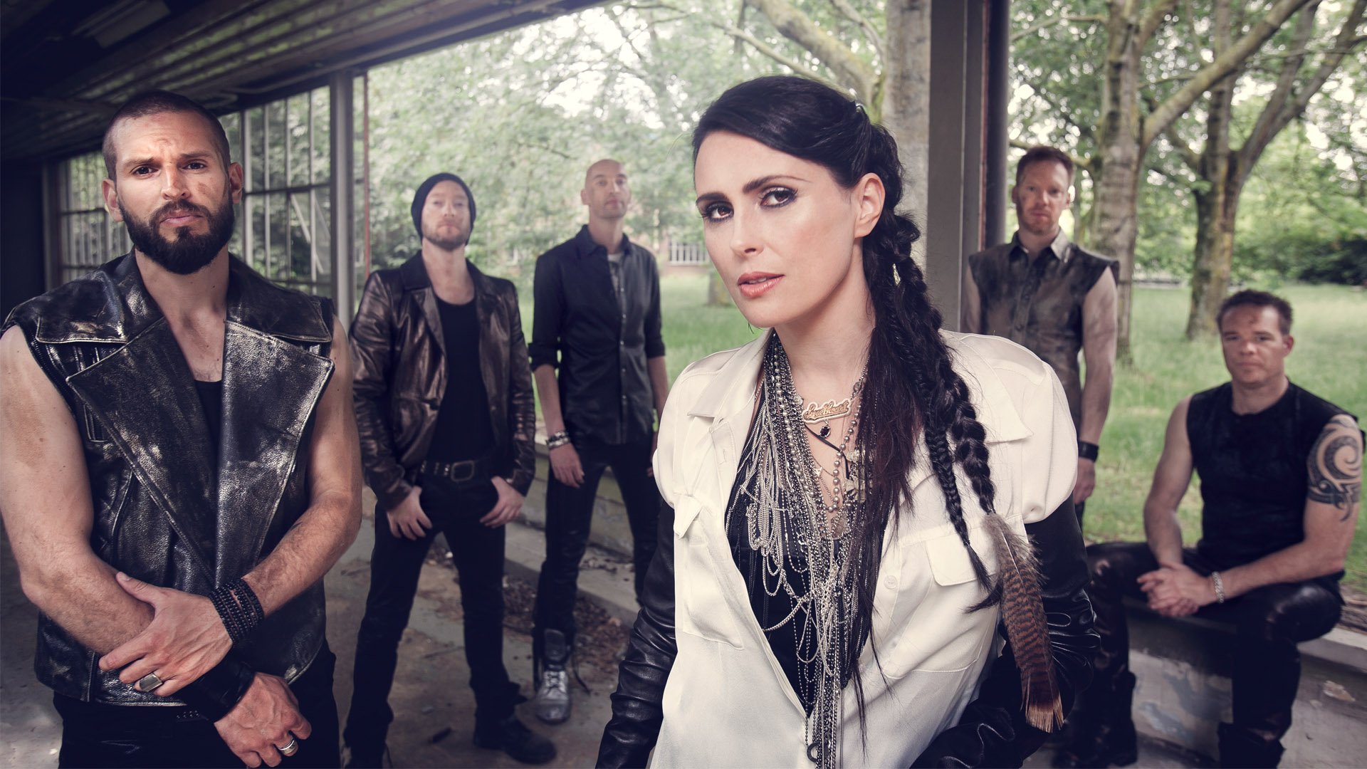 HD PC desktop wallpaper of a female-fronted symphonic metal band posing beneath a pavilion in moody woods; music — Within Temptation–inspired.