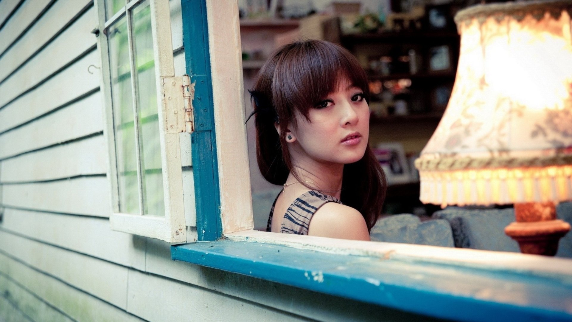 A Taiwanese woman sits by an open window in a cozy room decorated with shelves and a stylish lamp in this HD desktop wallpaper featuring Mikako Zhang Kaijie.