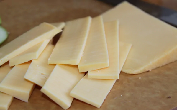 4K Ultra HD PC desktop wallpaper of sliced pale-yellow cheese on a wooden cutting board, food-themed background.
