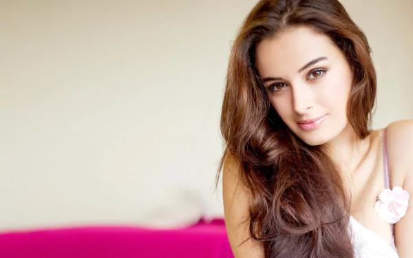 A stunning HD desktop wallpaper featuring celebrity Evelyn Sharma, showcasing her long, flowing hair and captivating smile against a soft, pink background.