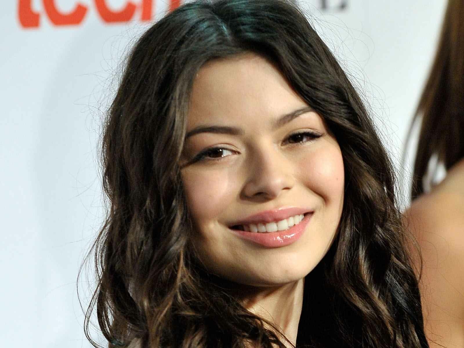 HD PC desktop wallpaper featuring a close-up portrait of celebrity Miranda Cosgrove smiling with natural makeup and loose dark hair.