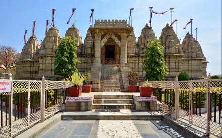 A stunning HD image of a temple in Chittorgarh, featuring intricate architecture, vibrant greenery, and decorative flags, perfect as a captivating desktop wallpaper or background.