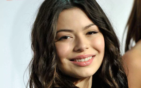 HD PC desktop wallpaper featuring a close-up portrait of celebrity Miranda Cosgrove smiling with natural makeup and loose dark hair.