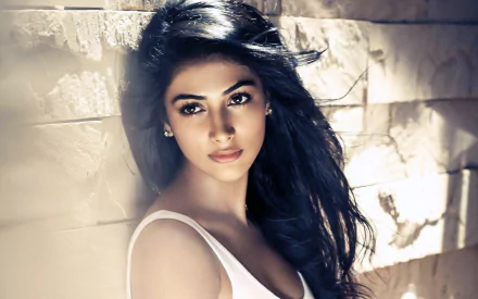 A stunning brunette actress from Bollywood, Pooja Hegde gazes thoughtfully at the camera, showcasing her beauty against a textured background in this HD desktop wallpaper.