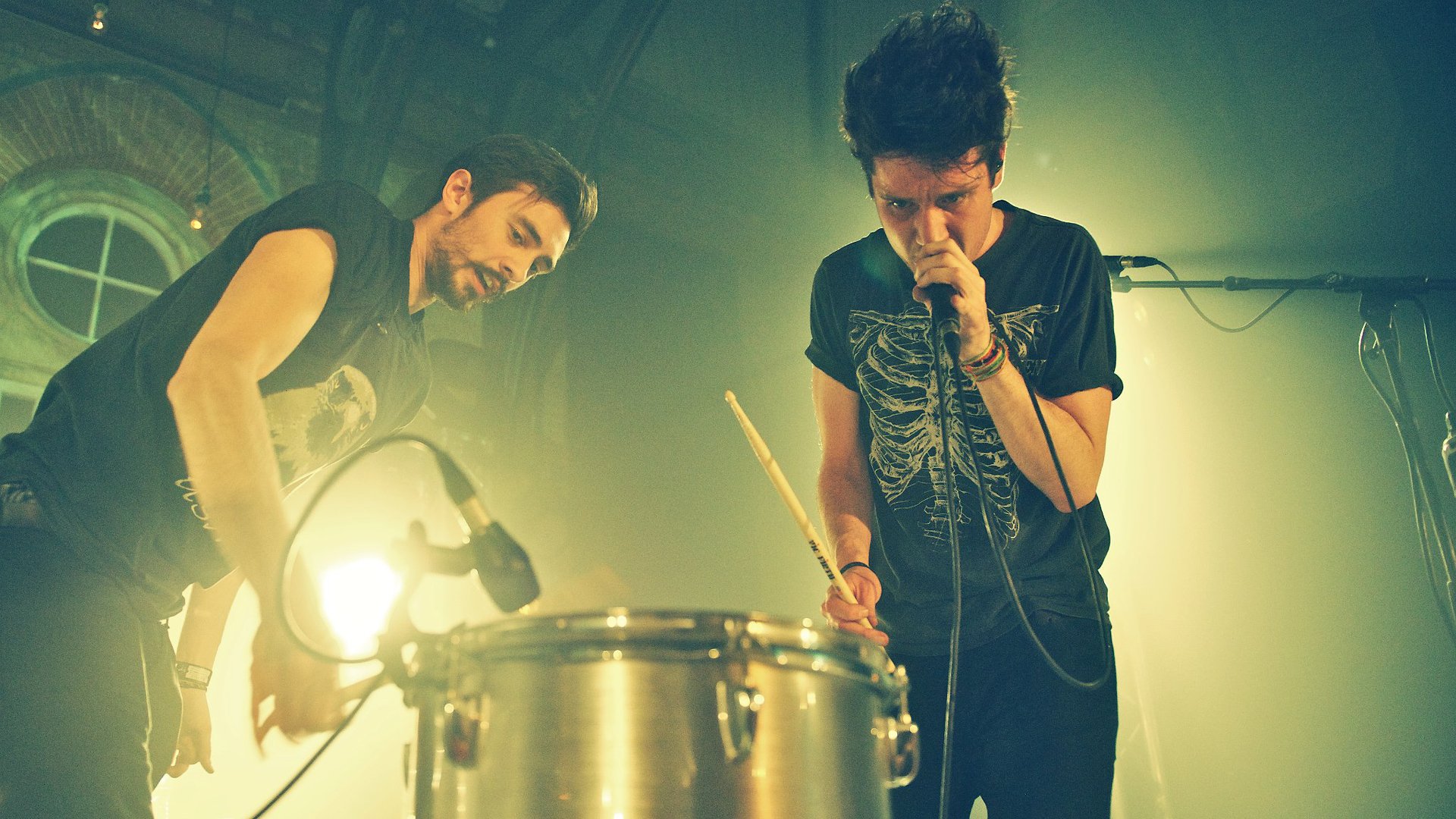 HD desktop wallpaper featuring Bastille, the English rock band, performing live with energetic stage presence and vibrant lighting.