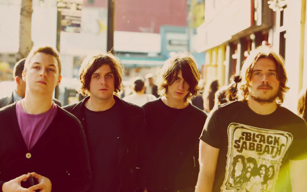 A high-definition desktop wallpaper featuring the rock band Arctic Monkeys, showcasing the band members walking together in an urban setting, embodying their English music style.