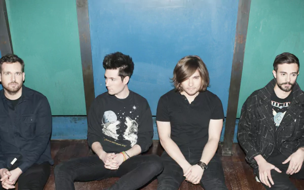 HD desktop wallpaper featuring the English rock band Bastille, with all four members seated against a blue and teal background.