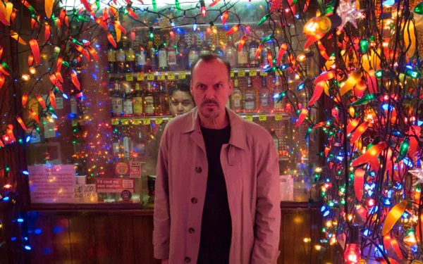 4K Ultra HD PC wallpaper of a brooding actor in a trench coat amid colorful string lights in a cramped bar, evoking the theatrical mood of Birdman.