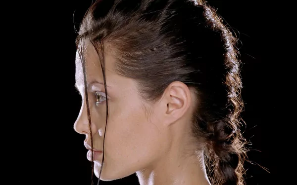 Close-up side profile of a braided woman against a black background, styled as Lara Croft: Tomb Raider — a 2K Quad HD PC desktop wallpaper and background.