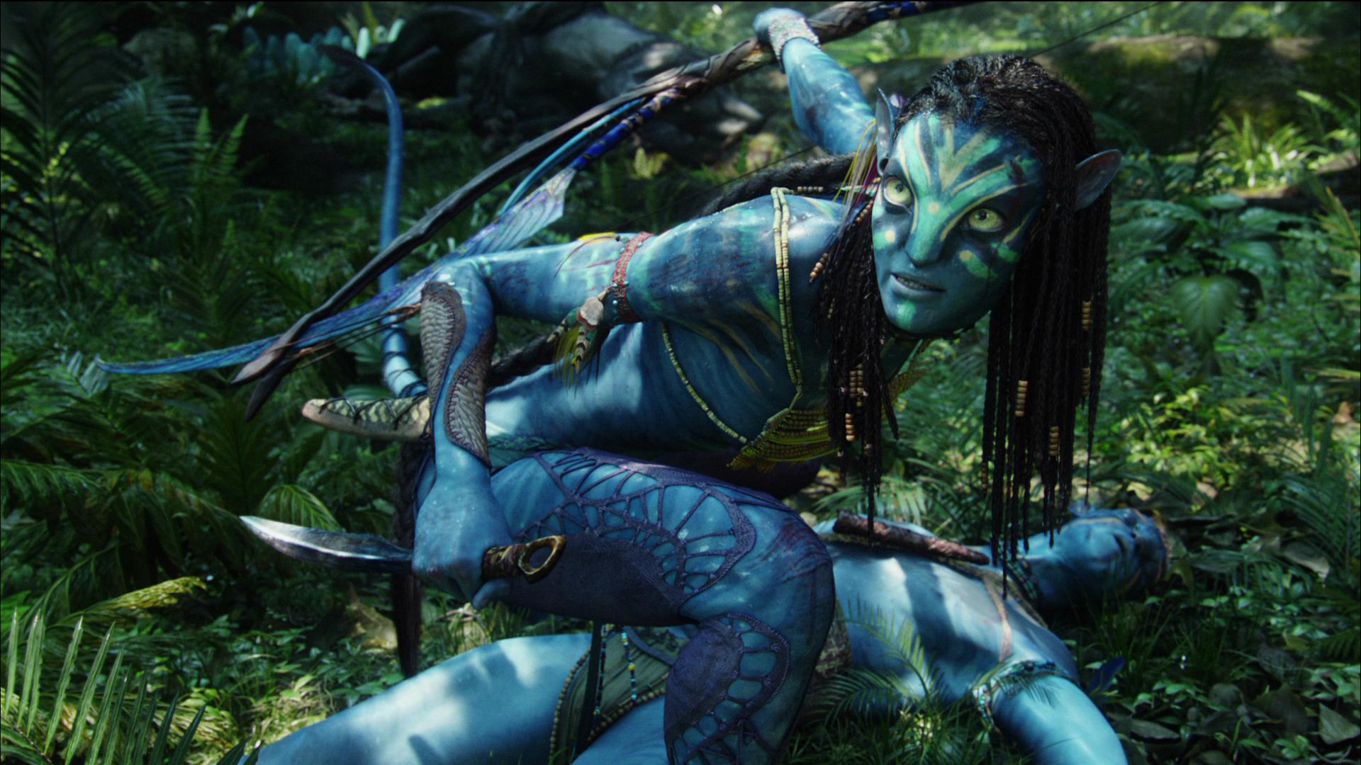 HD PC desktop wallpaper featuring a dynamic scene from the movie Avatar, showcasing a blue Na'vi character poised in a lush, vibrant forest setting.
