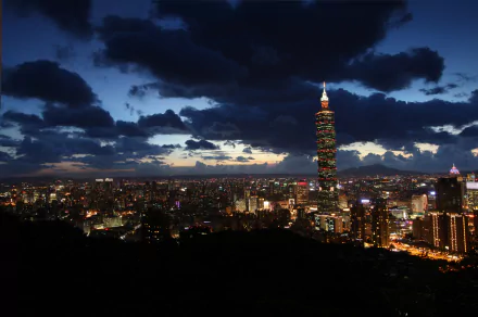 Nighttime cityscape of Taipei, Taiwan, featuring illuminated skyscrapers and clouds under a dark blue sky in 4K Ultra HD quality.