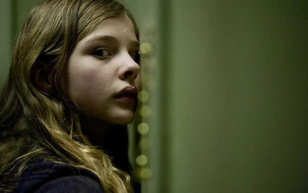 Chloë Grace Moretz in a haunting scene from the movie Let Me In, captured in this HD desktop wallpaper. Experience the chilling atmosphere of this compelling film.