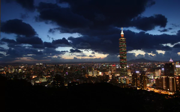 Nighttime cityscape of Taipei, Taiwan, featuring illuminated skyscrapers and clouds under a dark blue sky in 4K Ultra HD quality.