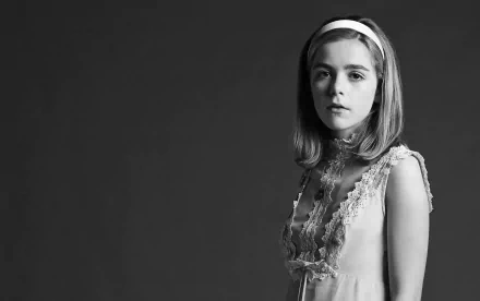 Black-and-white HD desktop wallpaper of a young female celebrity in a headband and lace dress, standing and gazing at the camera against a plain dark background.