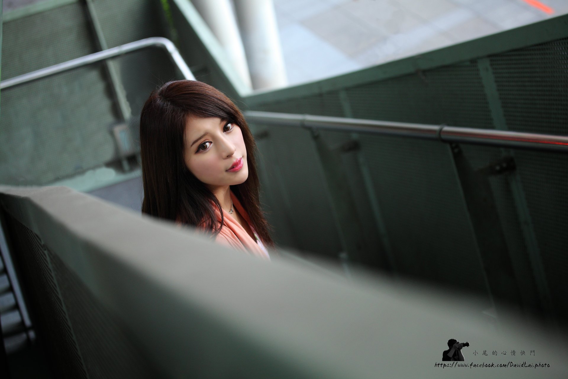 5K PC desktop wallpaper: Taiwanese model woman on a stairwell, long dark hair, soft directional light, gazing toward the camera with a quiet, contemplative expression.