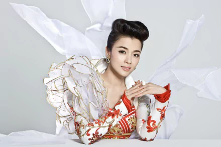 Smiling singer in ornate red-and-white musical costume, hands clasped against a soft white backdrop — 4K Ultra HD PC desktop wallpaper and background.