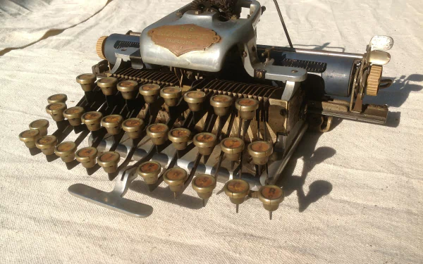 HD desktop wallpaper of a vintage man-made typewriter with round keys displayed on a textured fabric surface.