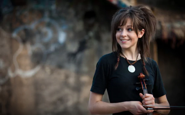 A vibrant HD wallpaper featuring Lindsey Stirling, smiling while holding her violin against a rustic background, capturing the essence of music and artistry.