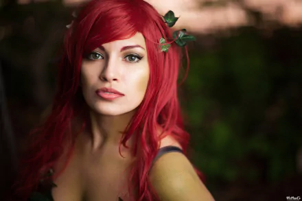A woman in vibrant red cosplay with ivy accents poses confidently, set against a blurred natural background, creating an engaging HD desktop wallpaper.
