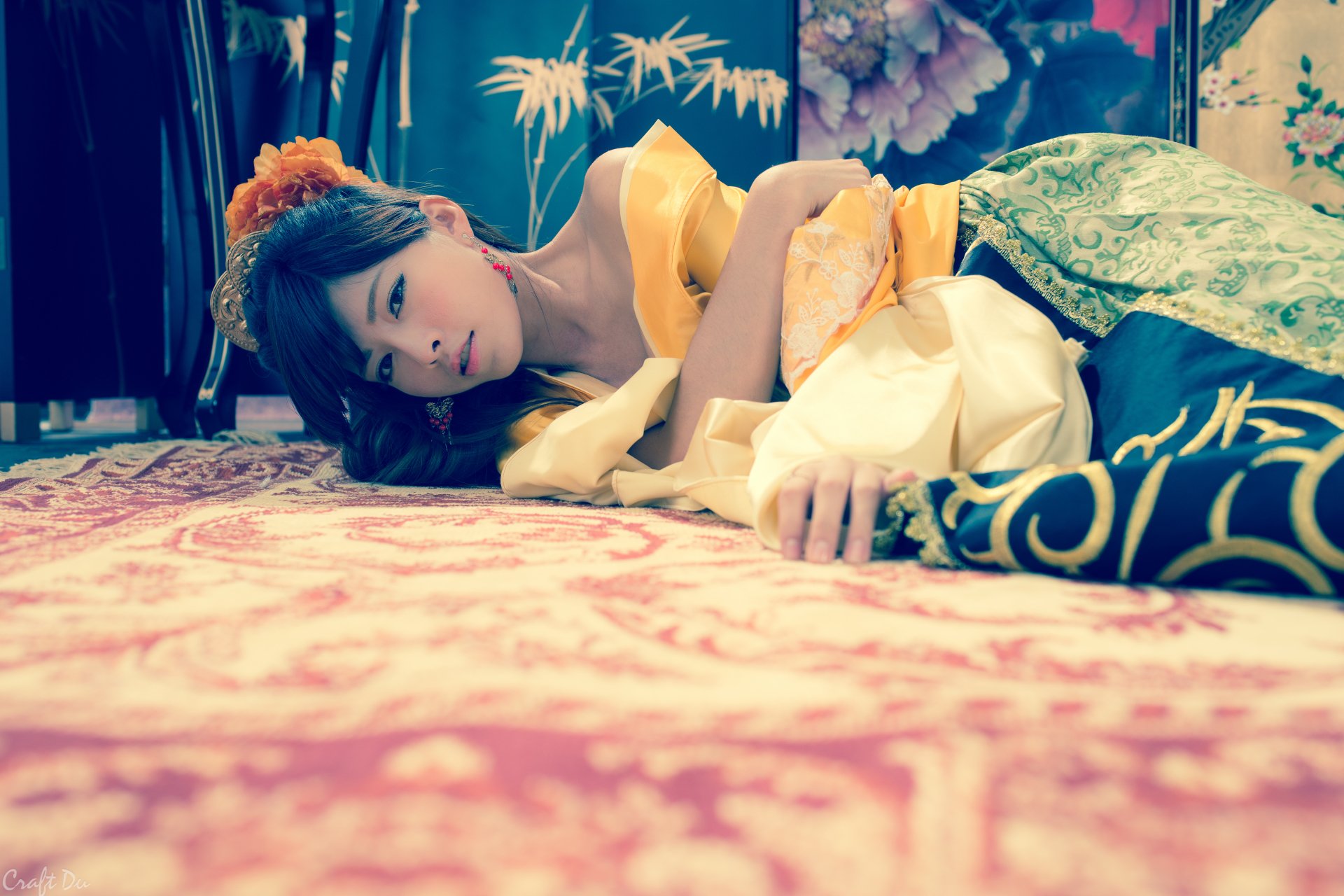 A Taiwanese woman in traditional silk costume lies on an ornate carpet, captured in 4K Ultra HD as a vibrant PC desktop wallpaper background.