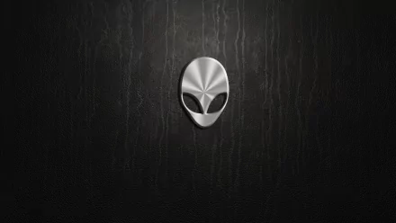 HD Alienware PC desktop wallpaper featuring a sleek metallic alien head emblem on a dark, textured technological background.