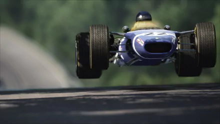 Low-angle view of a blue Lotus 49 racing car catching air on a tree-lined track in the video game Assetto Corsa — 2K Quad HD PC wallpaper.