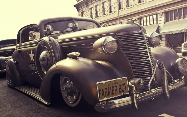 HD desktop wallpaper featuring a classic old timer vehicle with a vintage design parked on a street in front of historical buildings.
