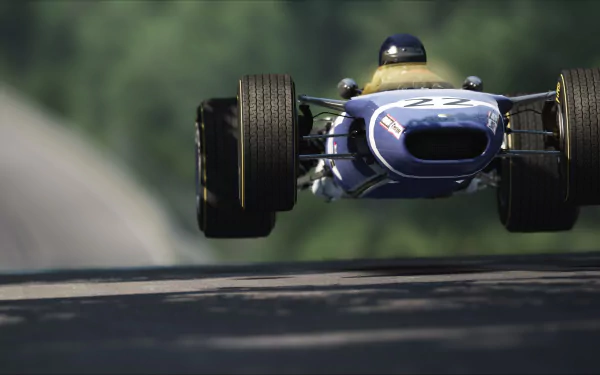 Low-angle view of a blue Lotus 49 racing car catching air on a tree-lined track in the video game Assetto Corsa — 2K Quad HD PC wallpaper.
