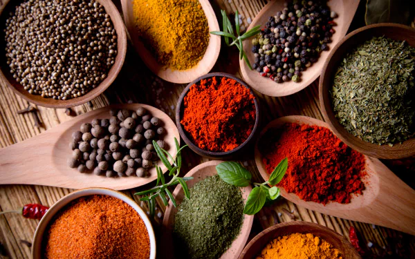 A vibrant 4K Ultra HD desktop wallpaper featuring an assortment of colorful herbs and spices artfully arranged in wooden spoons on a rustic surface.