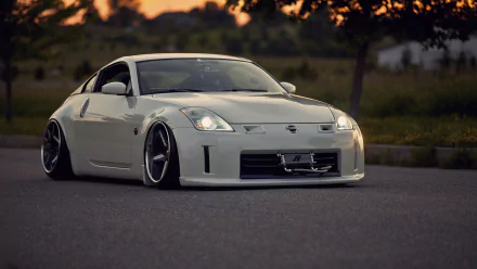 HD desktop wallpaper featuring a sleek white Nissan 350Z sports car parked on a road at sunset.