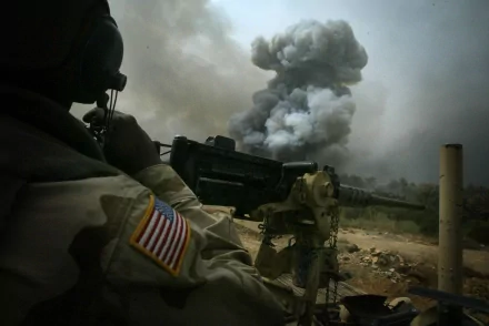 A United States Army soldier stands ready with heavy artillery as a plume of smoke rises in the background, captured in an HD desktop wallpaper and background.