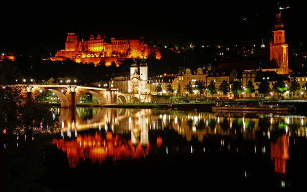 A stunning night view of Heidelberg Castle illuminated against the dark sky, reflecting beautifully on the river, showcasing the charm of this historic man-made landmark.
