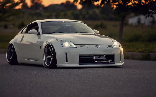 HD desktop wallpaper featuring a sleek white Nissan 350Z sports car parked on a road at sunset.